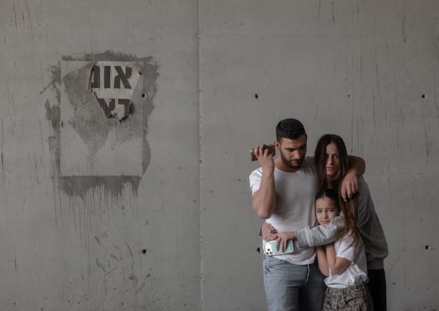 A family takes cover amid an Iranian ballistic missile attack in central Israel, March 26, 2026