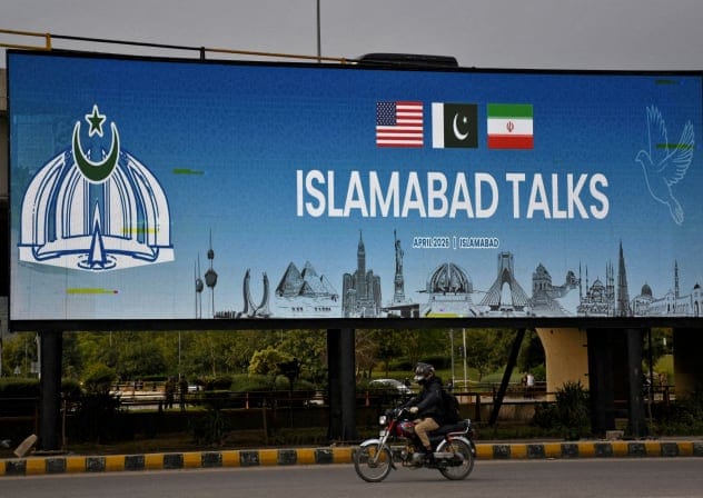 A man rides his motorbike past a billboard installed alongside a road as Pakistan prepares to host the U.S. and Iran for peace talks, in Islamabad, Pakistan, April 10, 2026. 