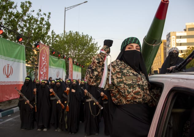 Women hold rifles in front of an Iranian flag during a pro-government National Army Day demonstration on April 17, 2026 in Tehran, Iran.