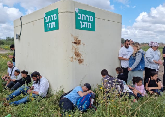 Israelis take cover around a small, overcrowded bomb shelter in a public park as sirens sound during Iranian missile attacks on April 6, 2026 in Hod Hasharon, central Israel.