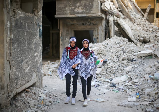  Two girls walk next to the rubble of a destroyed house in the Yarmouk camp on September 14, 2025 in Damascus, Syria. 