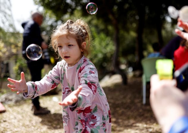 Shayna, a Jewish Ukrainian refugee from the Alumim children's home in Zhytomyr, Ukraine, catches bubbles as part of celebrations of the Jewish holiday of Purim after arriving to Israel following Russia's invasion of Ukraine.