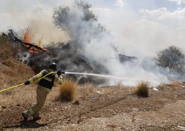 Firefighters douse flames in a field after a drone launched from southern Lebanon fell near Kibbutz Snir in the Upper Galilee.