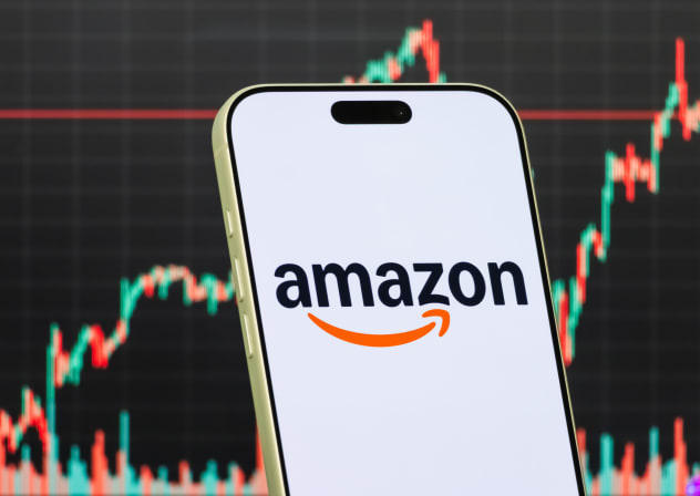 A smartphone displays the Amazon logo in front of a screen showing the company's latest stock market chart on January 29, 2026.
