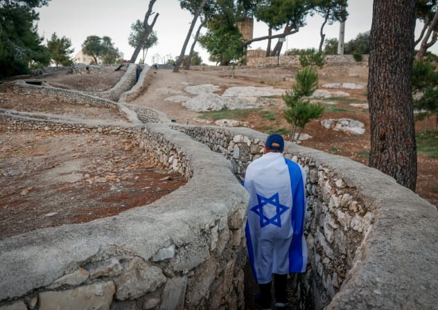 People wrapped in Israeli flags walk through the Ammunition Hill historic site in Jerusalem on June 2, 2024.