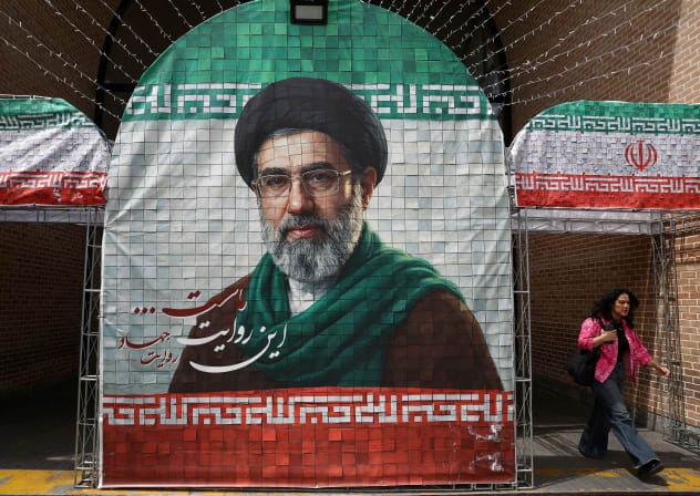 A woman walks next to a banner with a picture of Iran's new Supreme Leader Mojtaba Khamenei in Tehran, Iran, May 8, 2026. 