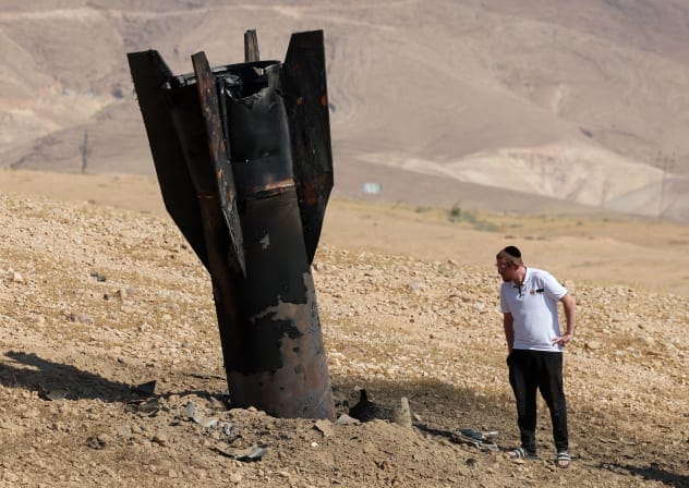 A man checks a fallen rocket half-buried in the ground in the West Bank on June 8, 2026, following Iranian and Iran-backed Houthi attacks.