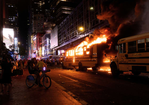 Revellers and fans celebrating the New York Knicks' win over the San Antonio Spurs and World Cup festivities watch as a city shuttle bus catches fire outside the Port Authority Bus Terminal in New York, U.S., June 14, 2026. The shuttles had been brought in to transport spectators to and from the New
