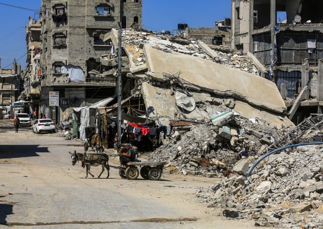 Palestinians walk among buildings destroyed during the recent war in Khan Younis, southern Gaza Strip, June 23, 2026.