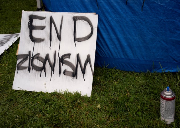 A sign that reads "end Zionism" leans against a tent, at a protest encampment in support of Palestinians, during the ongoing conflict between Israel and the Palestinian Islamist group Hamas, at Evergreen State College in Olympia, Washington, on April 28, 2024.