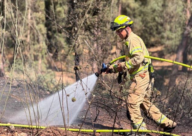 Firefighter works to extinguish the flames after a wildfire broke out in Samaria on July 18.