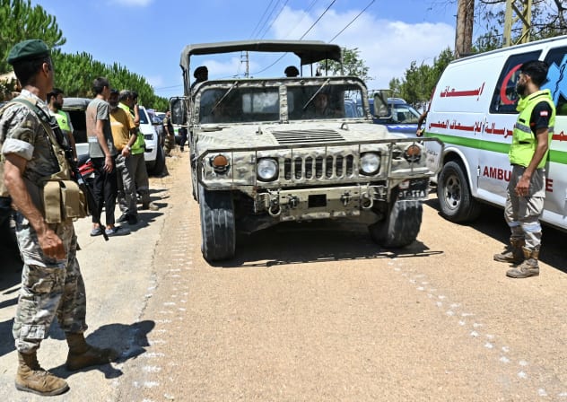 A Lebanese army vehicle drives past first responders near the entrance to the southern village of Zawtar al-Gharbiya as troops deploy to the village on July 21, 2026. 