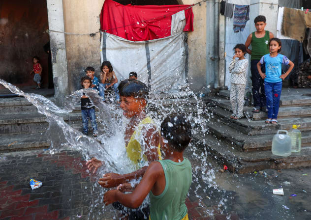 Displaced Palestinian children play in water as they shelter at a school on a hot day, in Khan Younis, in the southern Gaza Strip, July 1, 2026.