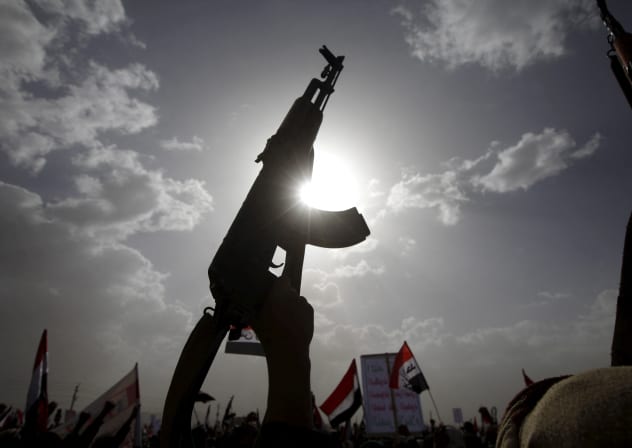 A Houthi follower rises a weapon as he attends a rally marking one year of Saudi-led air strikes, in Yemen's capital Sanaa.
