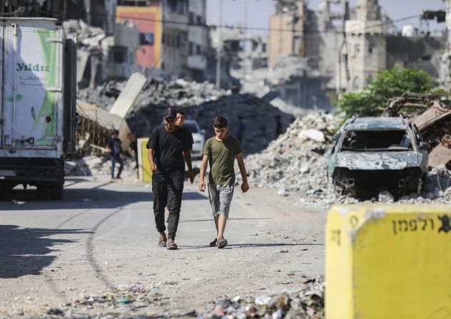 Palestinians walk next to yellow concrete block marking the “yellow zone” under Israeli military control in the Tufah neighborhood of Gaza City, July 27, 2026. 