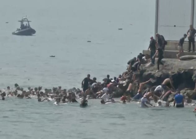 Migrants swim through Spain's Ceuta border from the Moroccan side and climb onto rocks to reach the border fence, in Ceuta, Spain, July 30, 2026, in this screen grab obtained from a video.