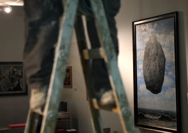 "The Castle of the Pyrenees" a painting by famous Belgian artist Rene Magritte is seen on a wall as a laborer on a ladder prepares the Israel Museum of Jerusalem for a re-opening.