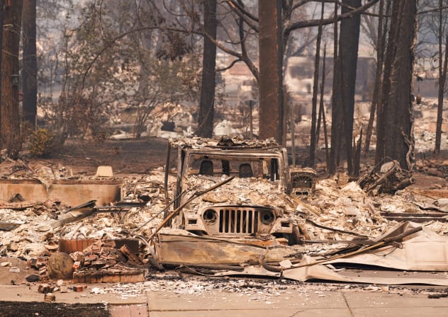 A burned car sits among an incinerated neighbourhood in the Old Trails Fire in Spokane, Washington.