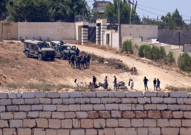  Israeli soldiers (top) stand guard next to settlers in front of the Palestinian houses in the village of Qusra, south of Nablus, in the occupied West Bank, on August 12, 2026.