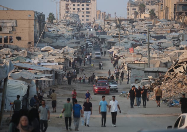 Displaced Palestinians walk past tents and destroyed buildings near the beachfront in Gaza City in August. 