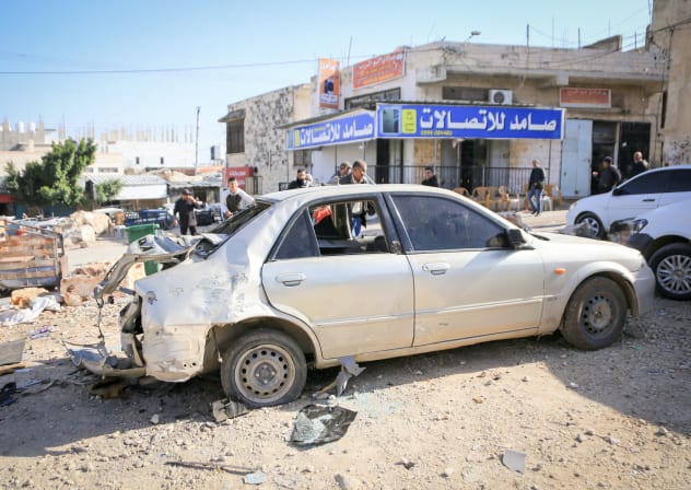 Palestinians stand at the site of a destroyed car blown up by Israeli forces during a military operation in the town of Qabatiya, south of Jenin in the northern West Bank; Illustrative.