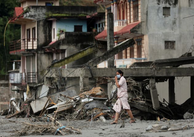 A woman walks past destroyed buildings after flash floods and mudslides, in Devighat, Nuwakot district, Nepal, August 29, 2026.