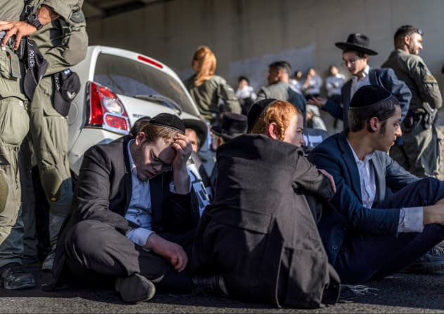 Police officers stand by as ultra-Orthodox men block a road during a protest against conscription into the IDF in Bnei Brak in August.