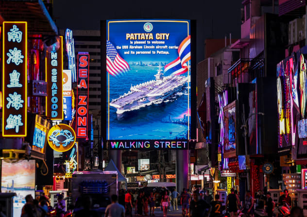 People walk past an LED display welcoming U.S. service personnel from the U.S. Nimitz-class aircraft carrier USS Abraham Lincoln, which is docked at Laem Chabang Port for a rest stop following a long deployment in the Middle East, in Pattaya City, Thailand, September 3, 2026.