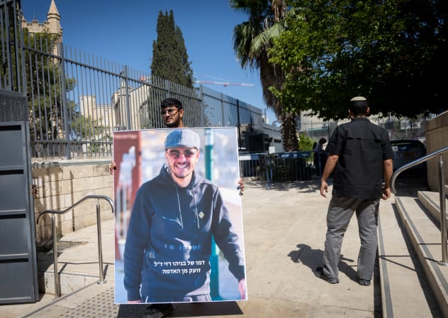 A young man holds an image of Beniyahu Razi who was murdered last month in Jerusalem, outside a court hearing on August 07, 2026.
