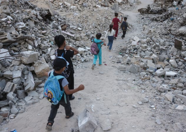 Palestinian children walk to school amid the rubble of destroyed buildings as the academic year begins in Khan Yunis, in the southern Gaza Strip on September 19, 2026. 