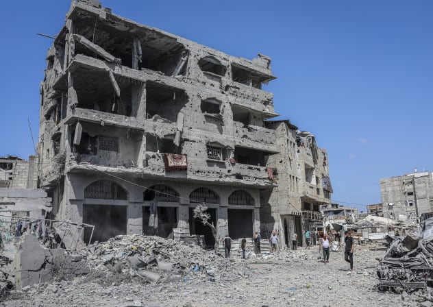 Residents stand near a heavily damaged residential building surrounded by rubble in the Al-Tuffah neighborhood of Gaza City, Gaza Strip on September 22, 2026. 