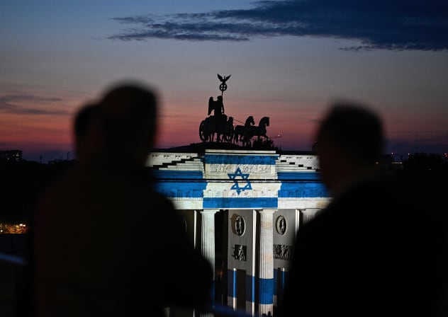 People look at Berlin's landmark Brandenburg Gate is illuminated with the Israeli flag in Berlin on October 7, 2026, the third anniversary of Hamas's October 7 attack on Israel.