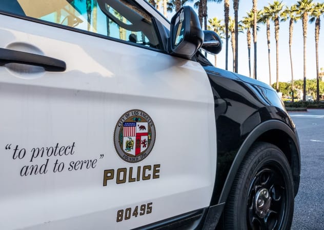 Los Angeles, USA - Close-up on the insignia and slogan of a LAPD vehicle, with the reflection of Union Station's tower visible in the car's window.