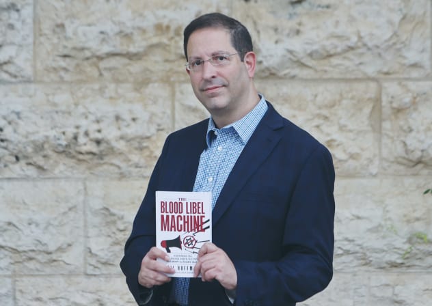 Author Gil Hoffman stands with his new book, ‘The Blood Libel Machine,’ which argues that the spread of anti-Israel narratives and the surge in global antisemitism were the result of a premeditated information campaign that had been in the works for decades. 