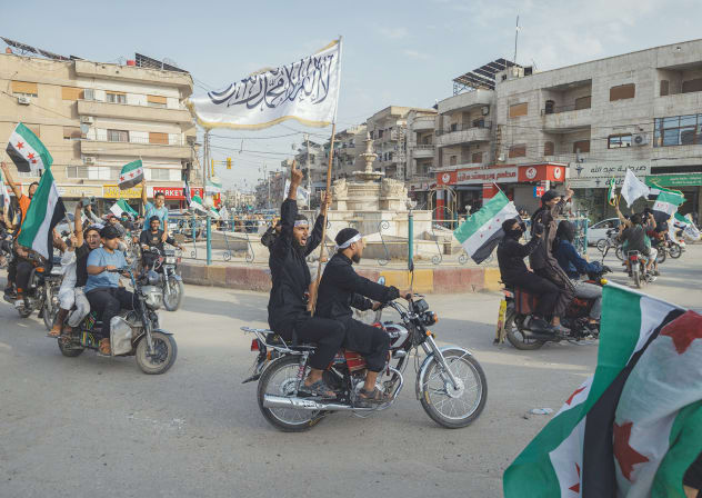 DEMONSTRATORS RIDE through a street while waving Syrian flags during a rally in Hasakah, Syria, last Friday. 