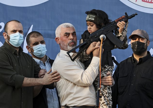 Hamas leader Yahya Sinwar holds the child of an Al-Qassam Brigades fighter, who was killed in the recent fighting with Israel, with a Kalashnikov rifle in his hand during a rally in Gaza City on May 24, 2021.