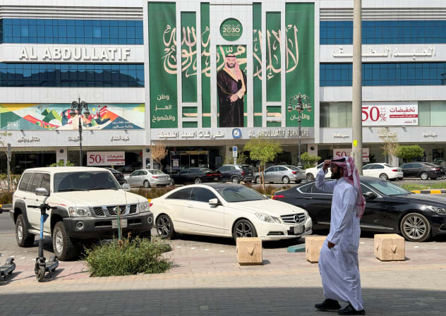 A Saudi man walks past a banner of Saudi Crown Prince Mohammed bin Salman displayed on a commercial building in Riyadh, Saudi Arabia, October 15, 2026.