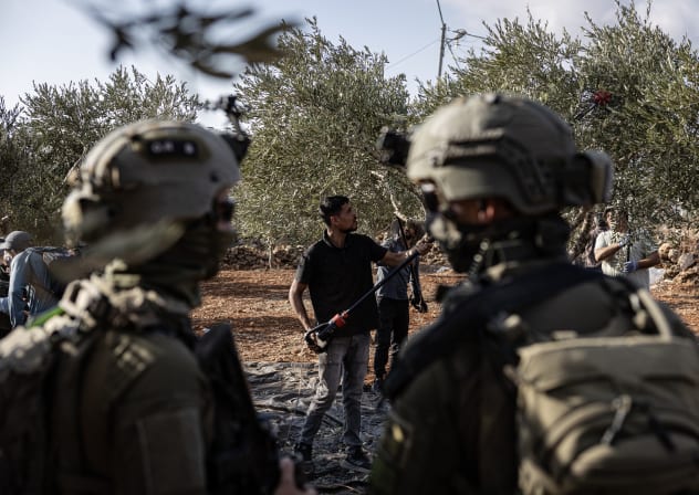 Israeli soldiers watch Palestinian farmers and foreign volunteers in Area B during the olive harvest on October 17, 2026 in Abu Falah, West Bank. 