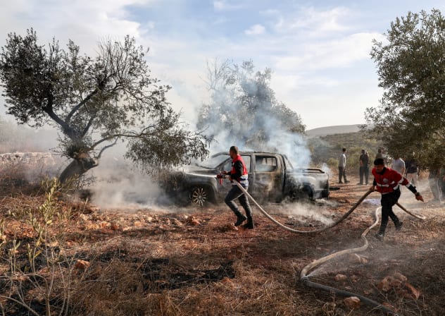 Firefighters douse a burnt car with water after Israeli settlers attacked a group of Palestinians harvesting olives near Turmus Ayya in the West Bank, October 16, 2026. 