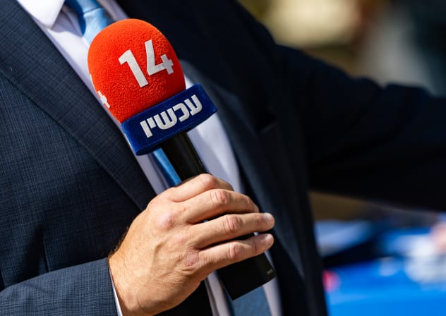  reporter holds a microphone of Israel’s Channel 14 news at a polling station during the Likud primary elections in Jerusalem, August 17, 2026.