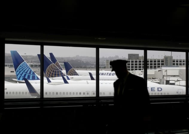 A pilot walks by United Airlines planes as they sit parked at gates at San Francisco International Airport.