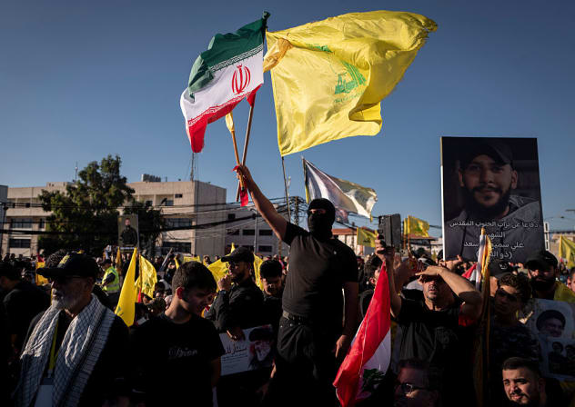 A man attending a ceremony marking the second anniversary of the assassination of Hezbollah leader Hassan Nasrallah and holding an Iranian and a Hezbollah flag on September 27, 2026 in Beirut, Lebanon.  