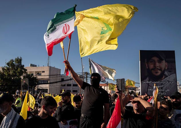 A man attending a ceremony marking the second anniversary of the assassination of Hezbollah leader Hassan Nasrallah and holding an Iranian and a Hezbollah flag on September 27, 2026 in Beirut, Lebanon.  