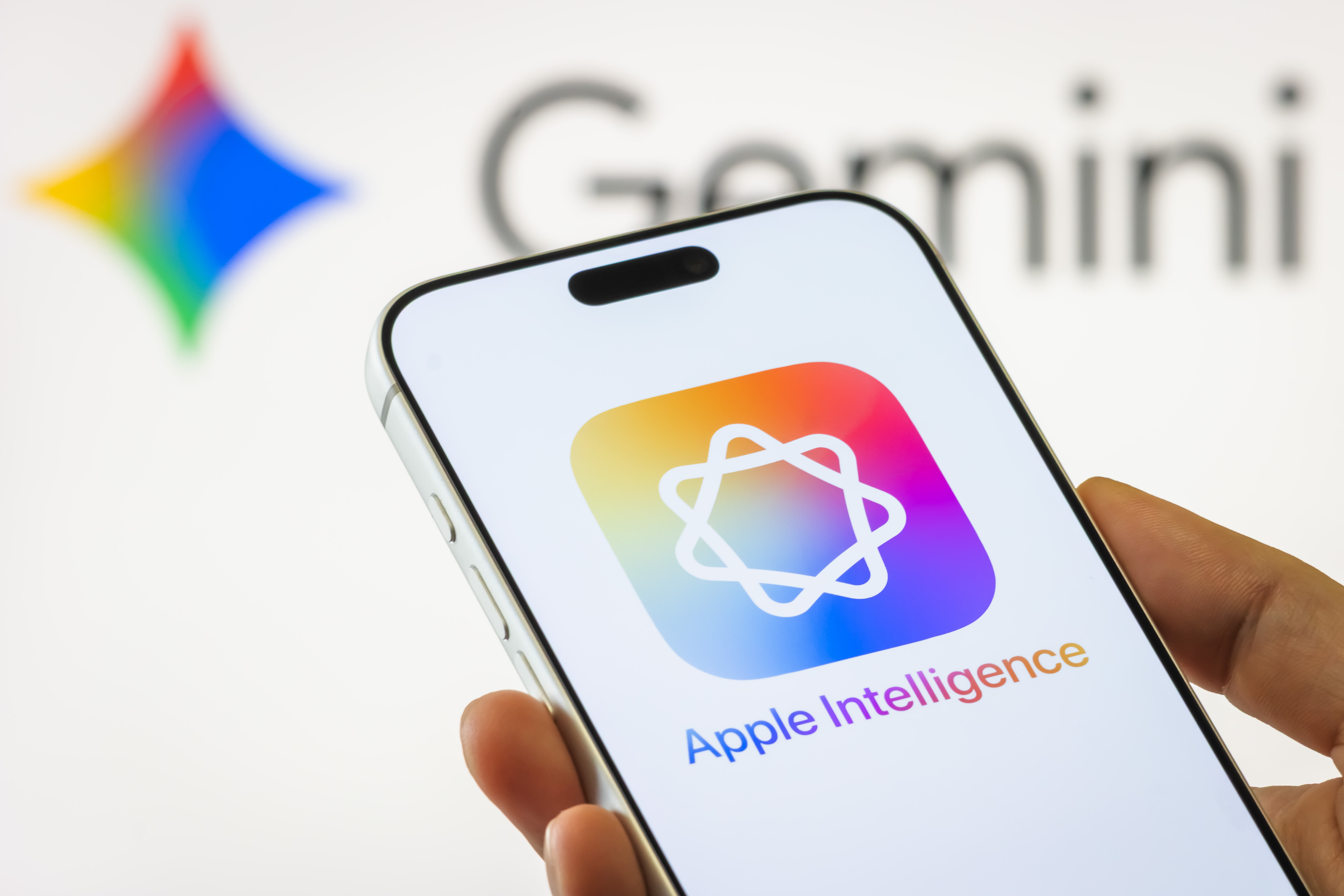 In this photo illustration, an Apple iPhone displays the Apple Intelligence logo against a blurred background featuring the Google Gemini logo on January 13, 2026, in Chongqing, China. (photo credit: Cheng Xin/Getty Images)