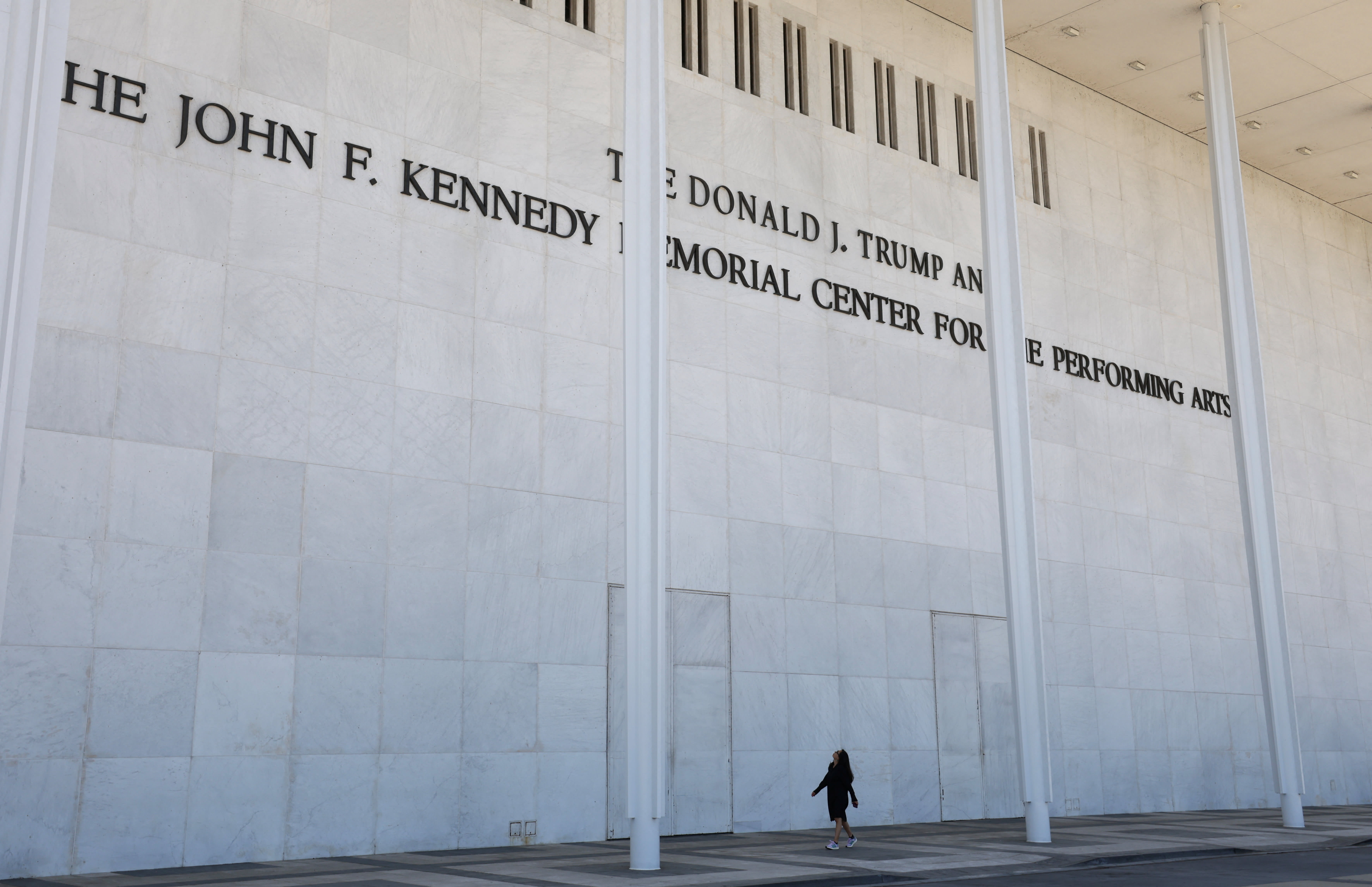 A woman looks up as she passes the front of the John F. Kennedy Memorial Center for the Performing Arts, renamed The Donald J. Trump and The John F. Kennedy Memorial Center for the Performing Arts by the Trump administration, after a federal judge ordered that U.S. President Trump’s name be removed  (photo credit: REUTERS/KEVIN LAMARQUE)