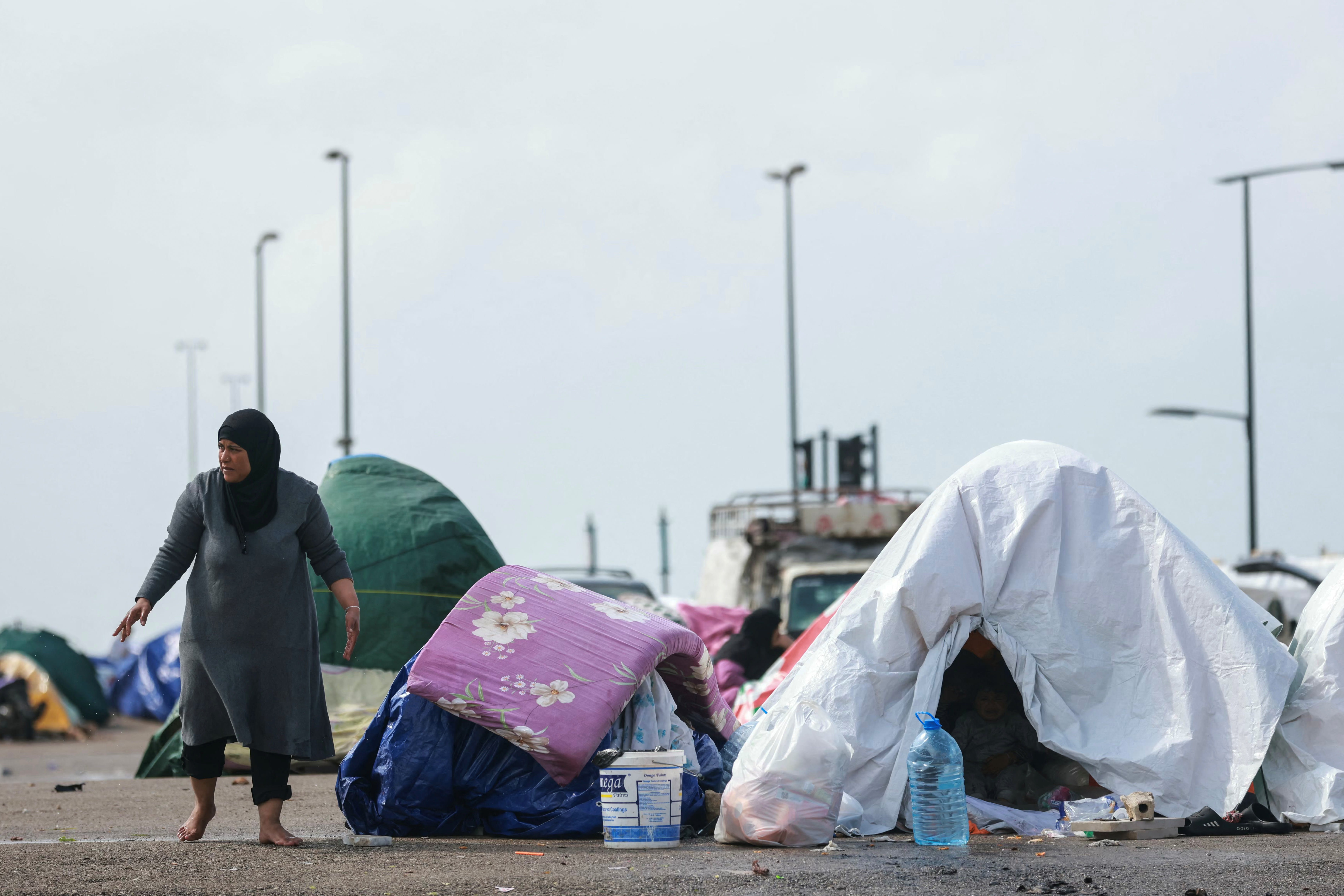 A displaced Lebanese woman stands beside her tent along Beirut’s seafront area on March 15. Israel issued evacuation orders covering hundreds of square kilometers of Lebanon, displacing hundreds of thousands of people.  (photo credit: IBRAHIM AMRO/AFP via Getty Images)