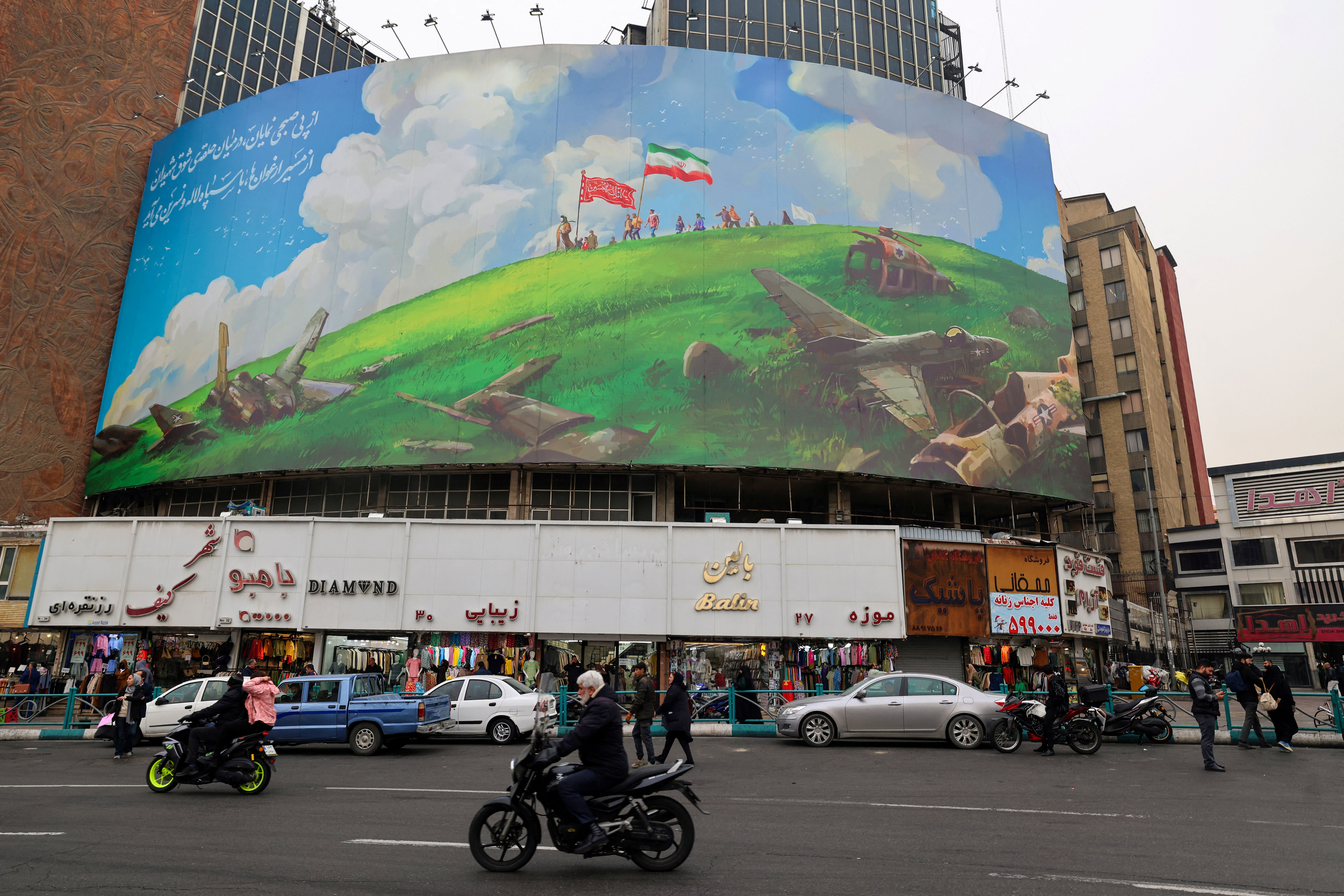 An Iranian rides a moped past a huge anti-US billboard displayed on a building in Tehran