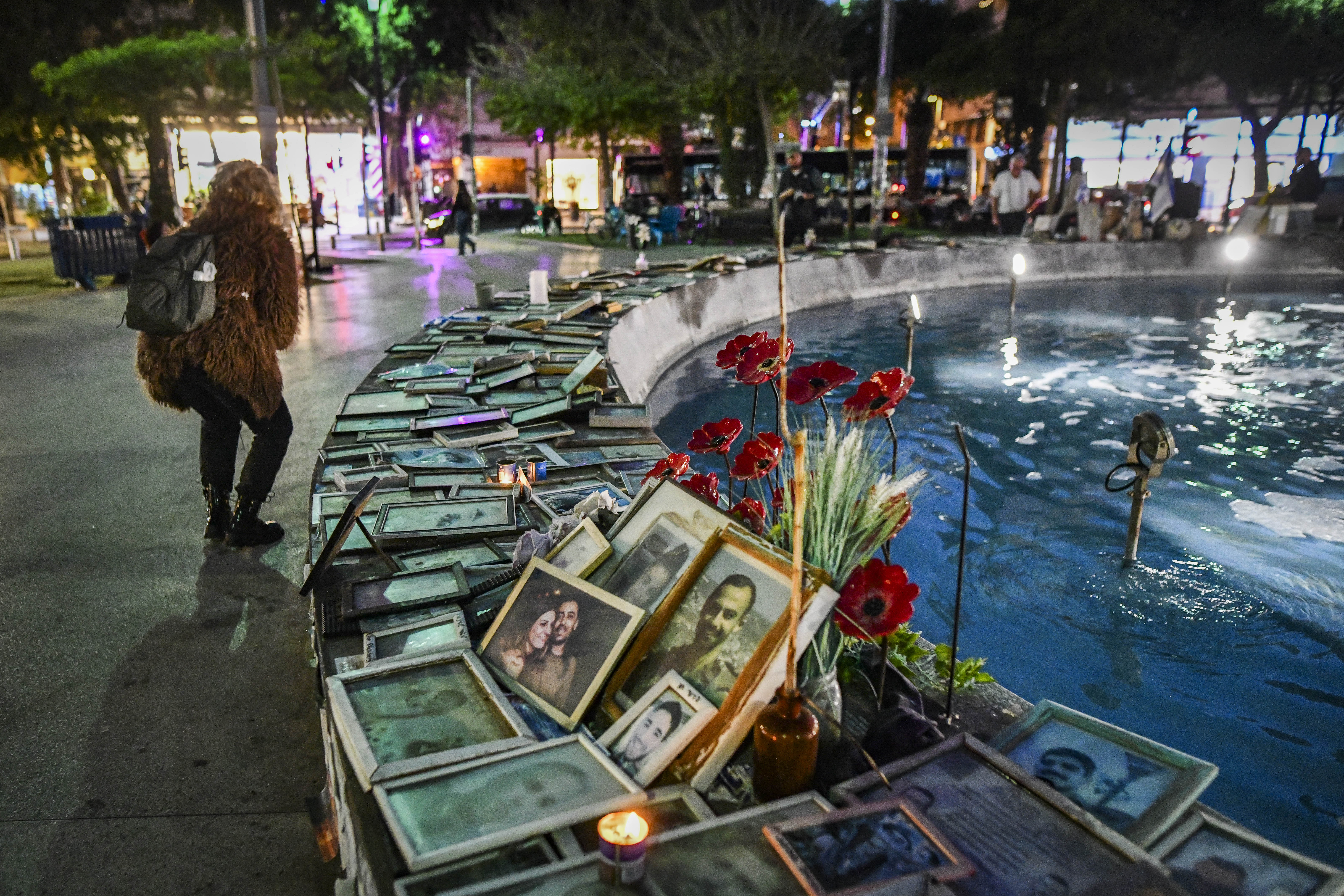 People next to photos of victims of terror attacks and fallen Israeli soldiers at Dizengoff Square in Tel Aviv on the eve of Israel’s Memorial Day, April 20, 2026. (photo credit: AVSHALOM SASSONI/FLASH90)