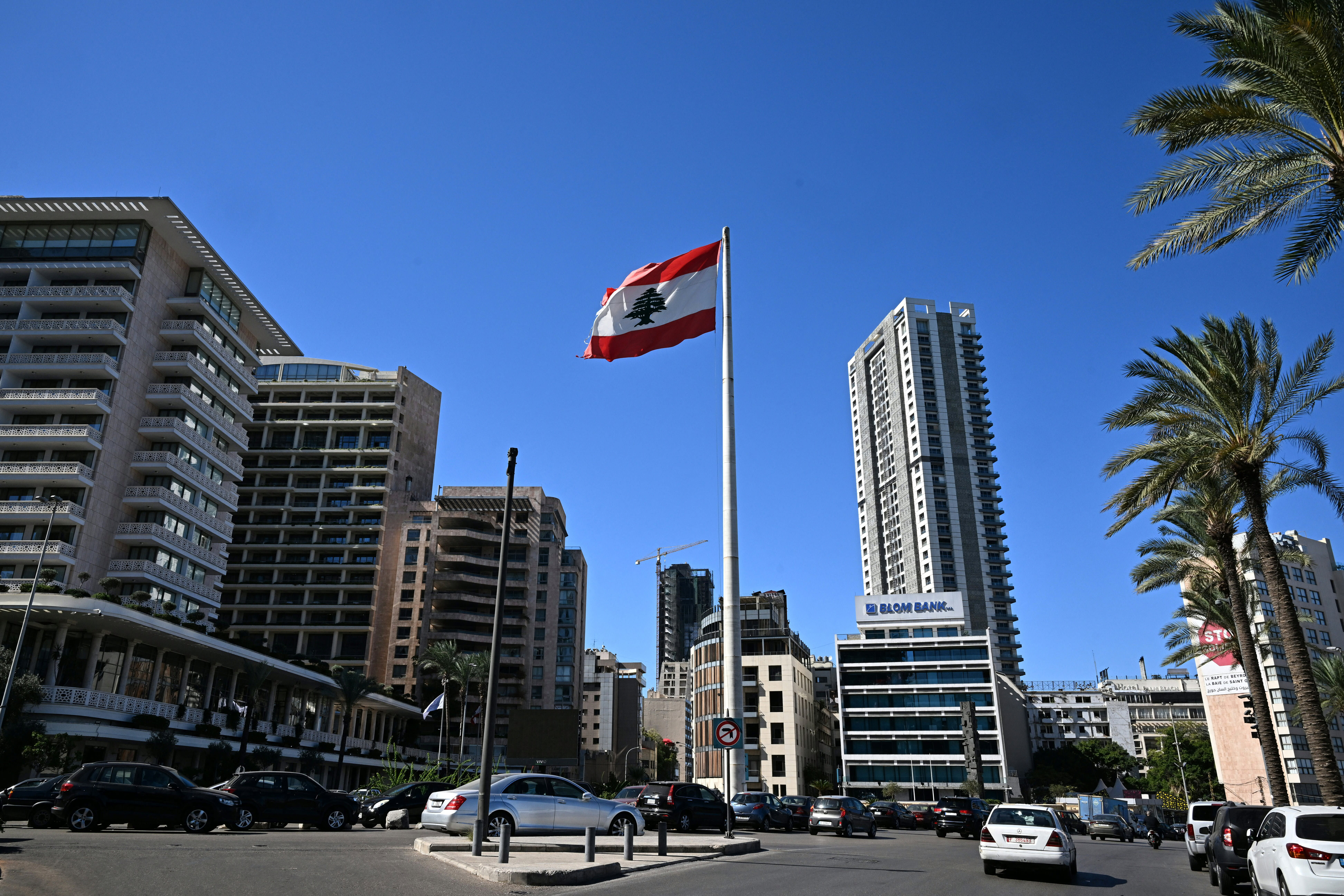 People drive past a Lebanese national flag fluttering in a square in central Beirut on October 21, 2024. (photo credit: JOSEPH EID/AFP via Getty Images)