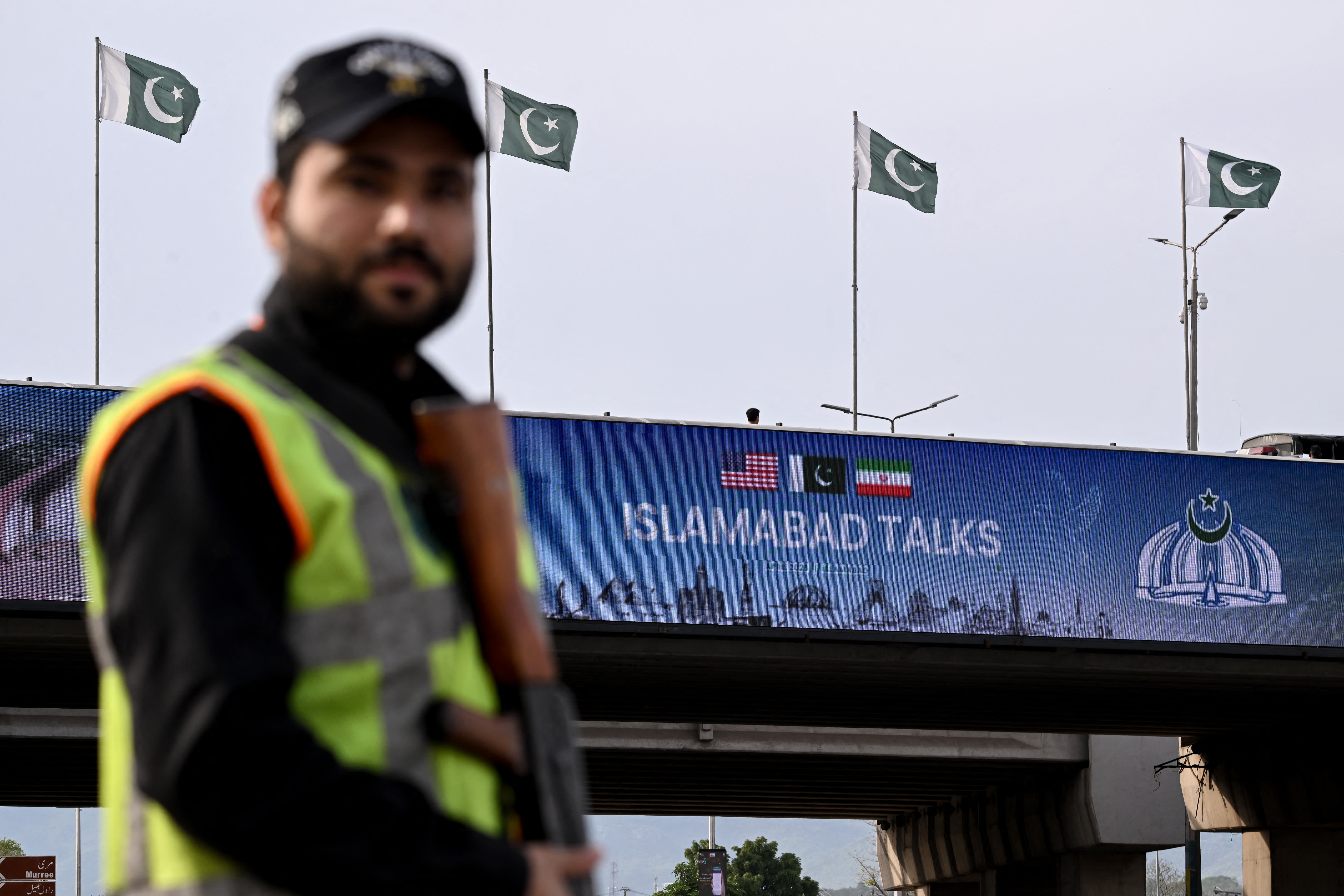 A policeman stands guard in front of a digital screen displaying news of USIran peace talks along a road in Islamabad on April 10, 2026. (photo credit: Farooq NAEEM / AFP via Getty Images)